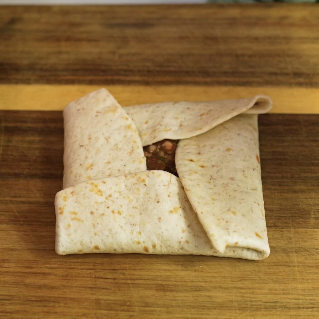 Fully folded tortilla parcel ready for baking.