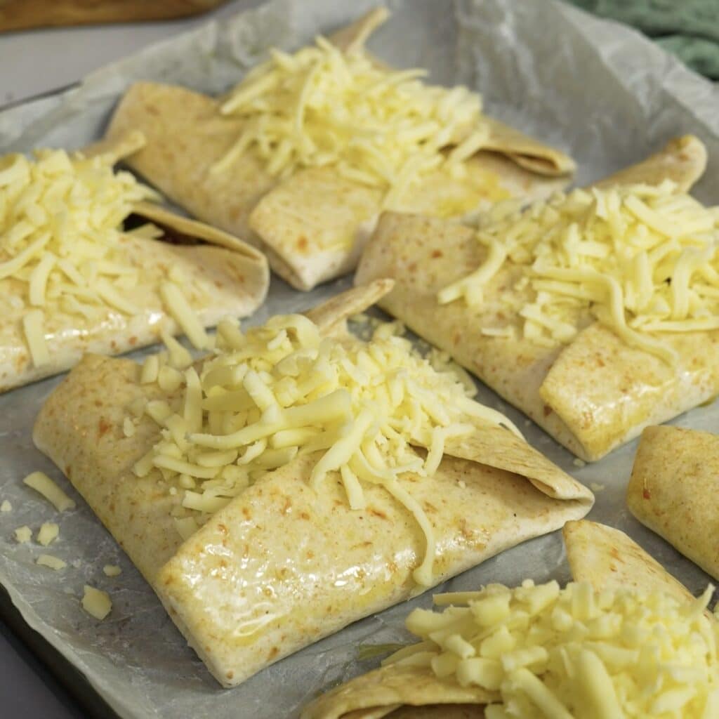 Tortilla parcels on a baking tray brushed with olive oil and topped with mozzarella.