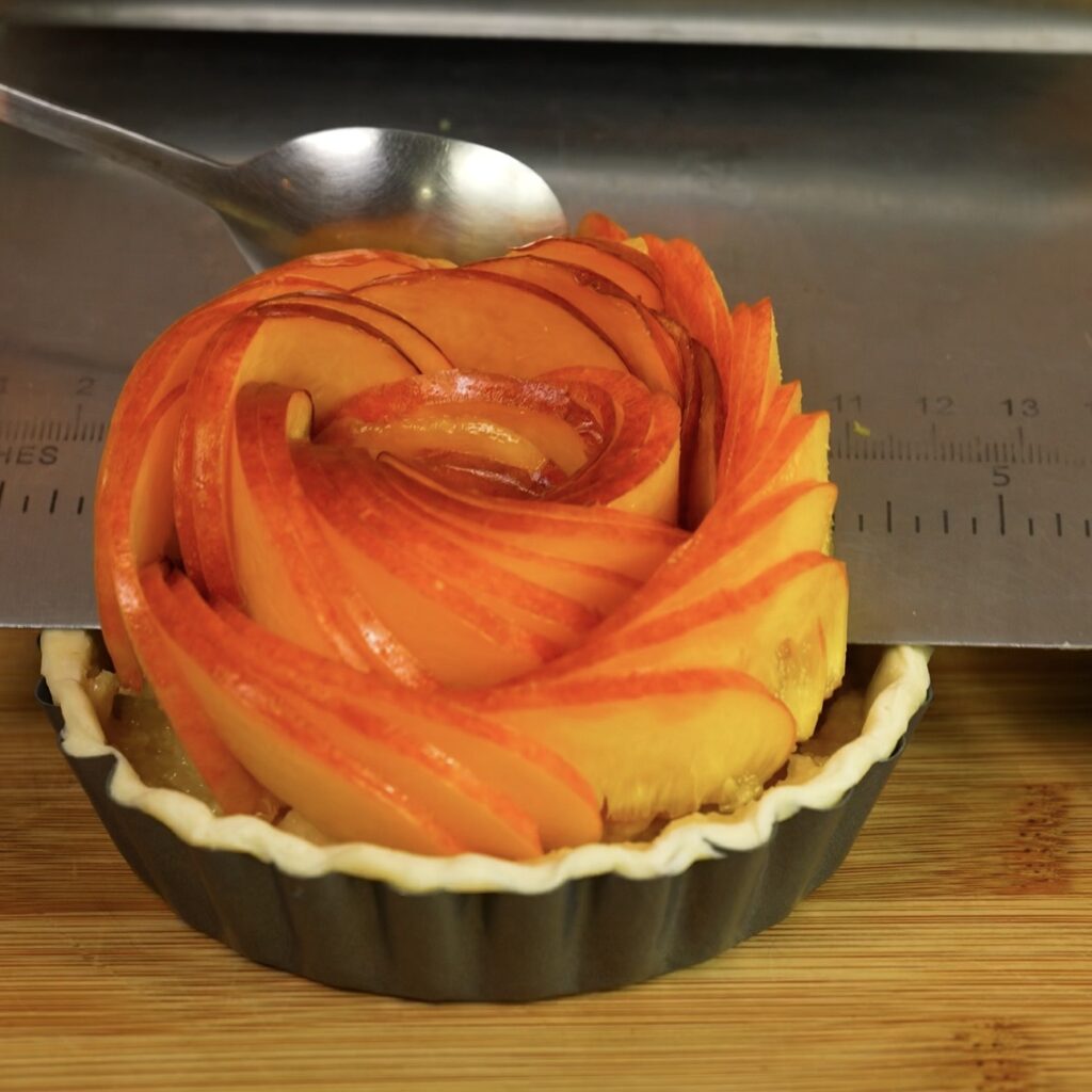 Adding sliced nectarines on top of frangipane tartlets
