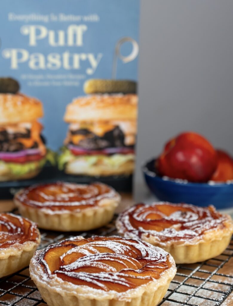 Baked nectarine frangipane tartlets with cookbook in the background