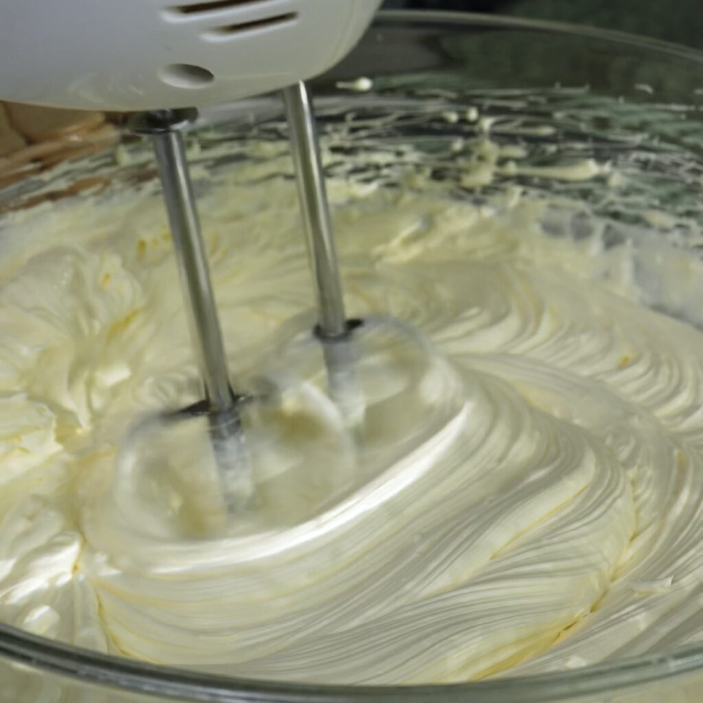 Whipping mascarpone cream with double cream and icing sugar in a bowl