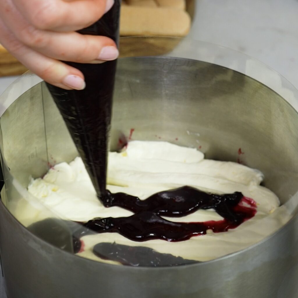 Piping blueberry sauce over mascarpone cream layer