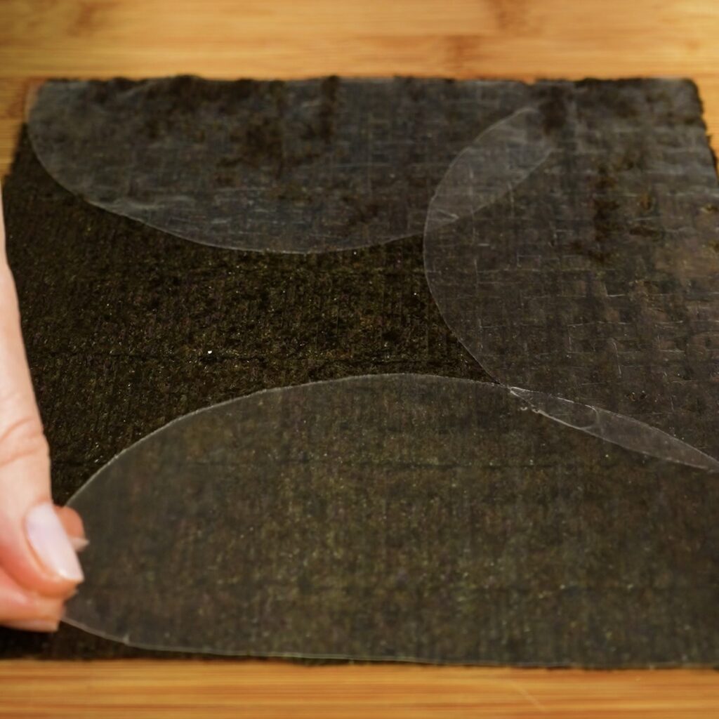 Placing rice paper halves on a nori sheet to create the base for crispy salmon squares