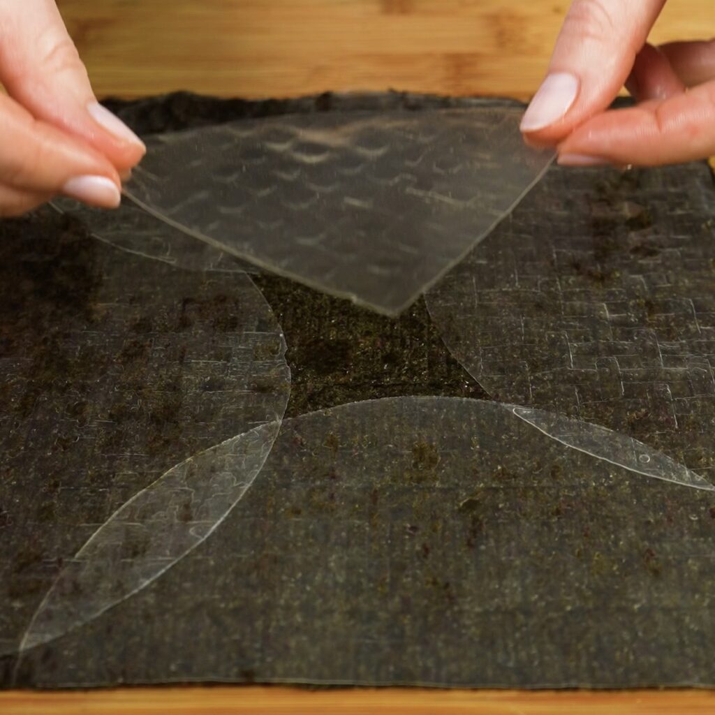 Adding the final quarter of rice paper to fully cover the nori sheet for crispy salmon squares