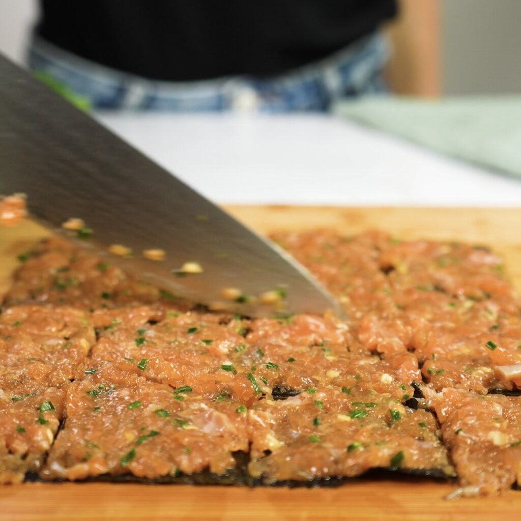 Cutting salmon-topped nori and rice paper into squares