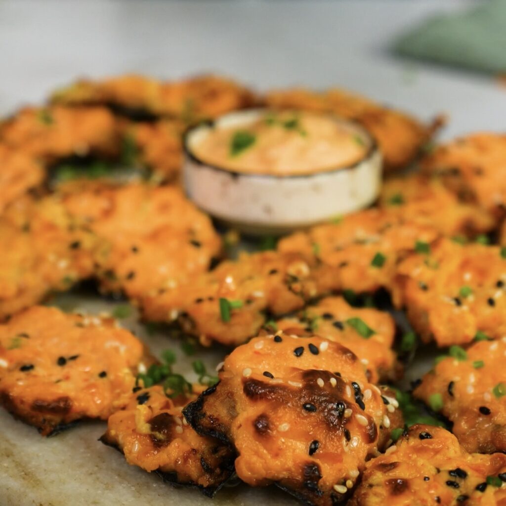 Crispy salmon squares served on a board with chives and sesame seeds