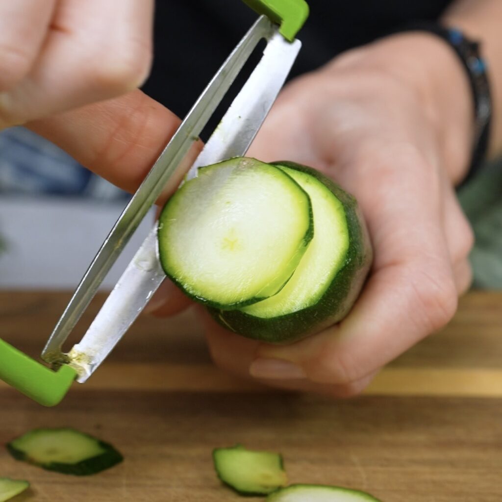 Slicing courgette into thin ribbons with a wide vegetable peeler
