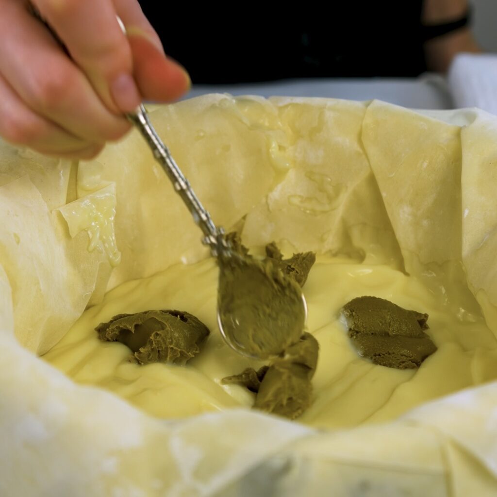 Spreading custard and adding pistachio cream over filo layers