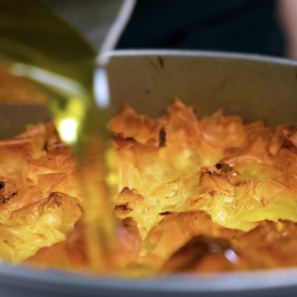 Pouring cooled syrup over hot baklava cake