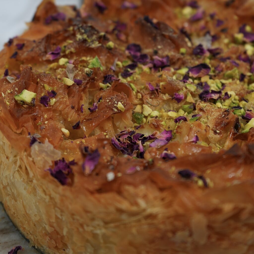 Baklava cake topped with crushed pistachios and rose petals