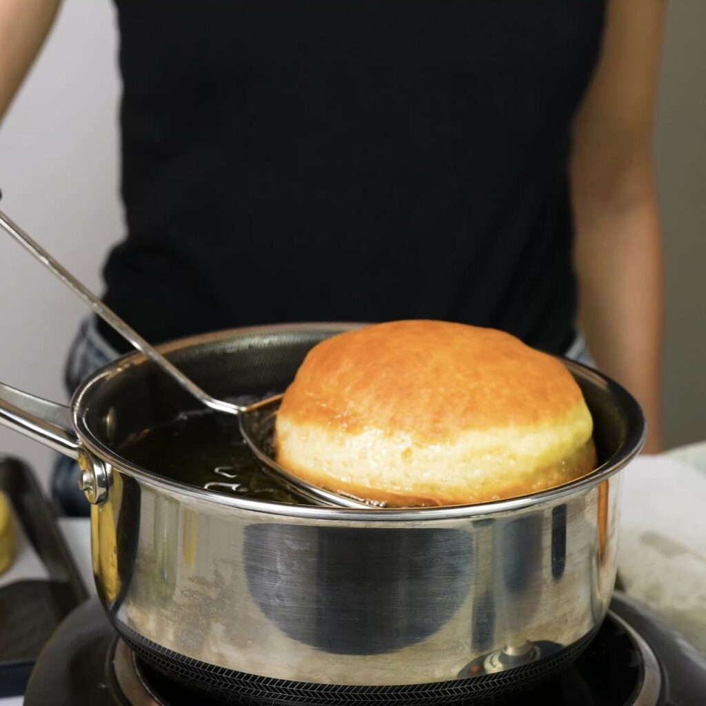 Doughnuts frying in hot oil until golden