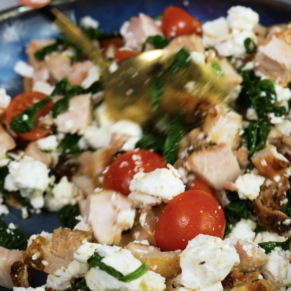 Mixing chicken, feta, spinach and cherry tomatoes for the puff quiches filling.
