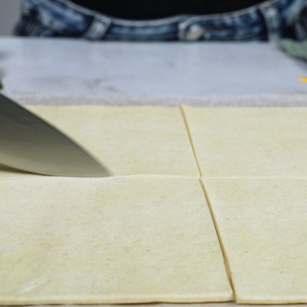 Cutting puff pastry into six equal squares.