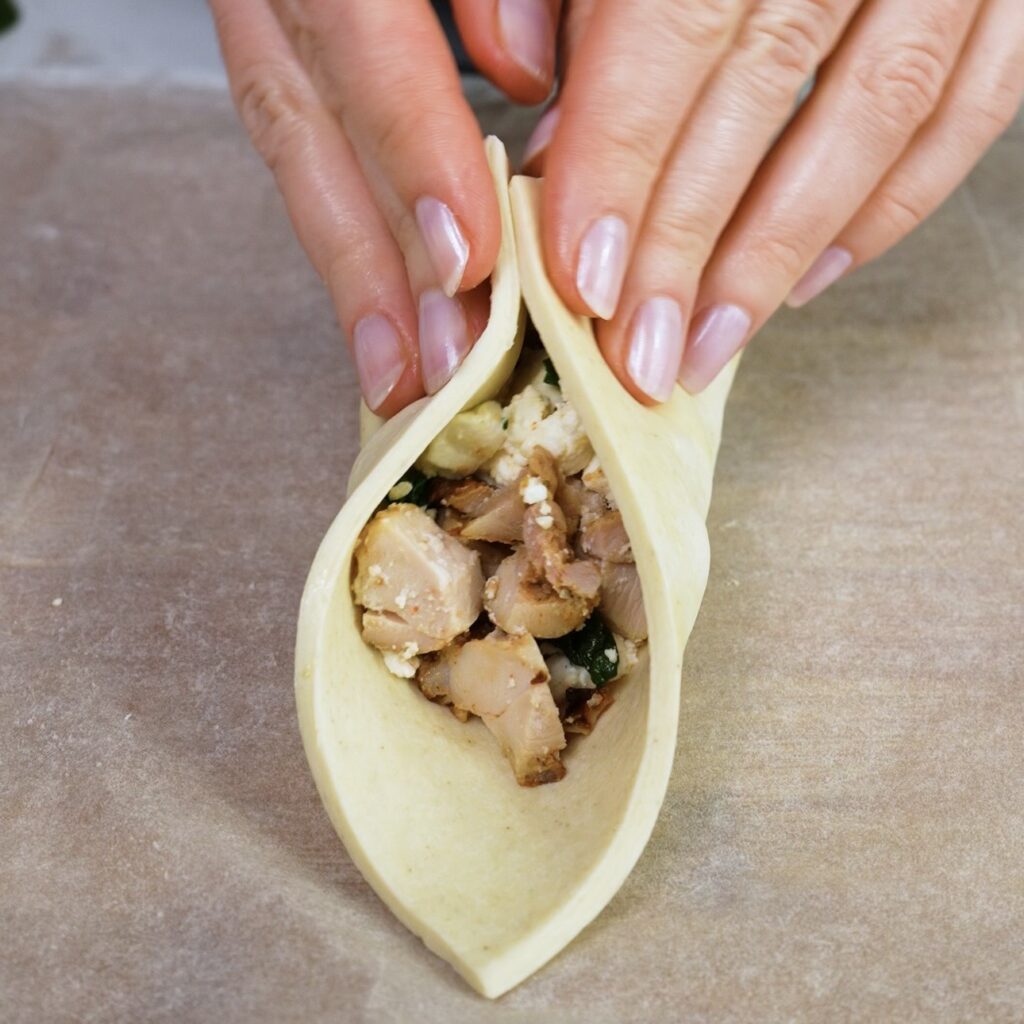 Sealing opposite corners of the puff pastry over the filling.