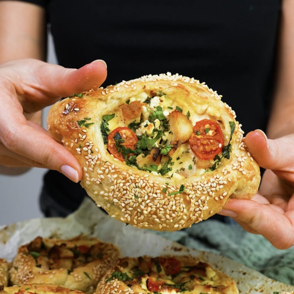 Hands holding a freshly baked chicken and feta puff quiche