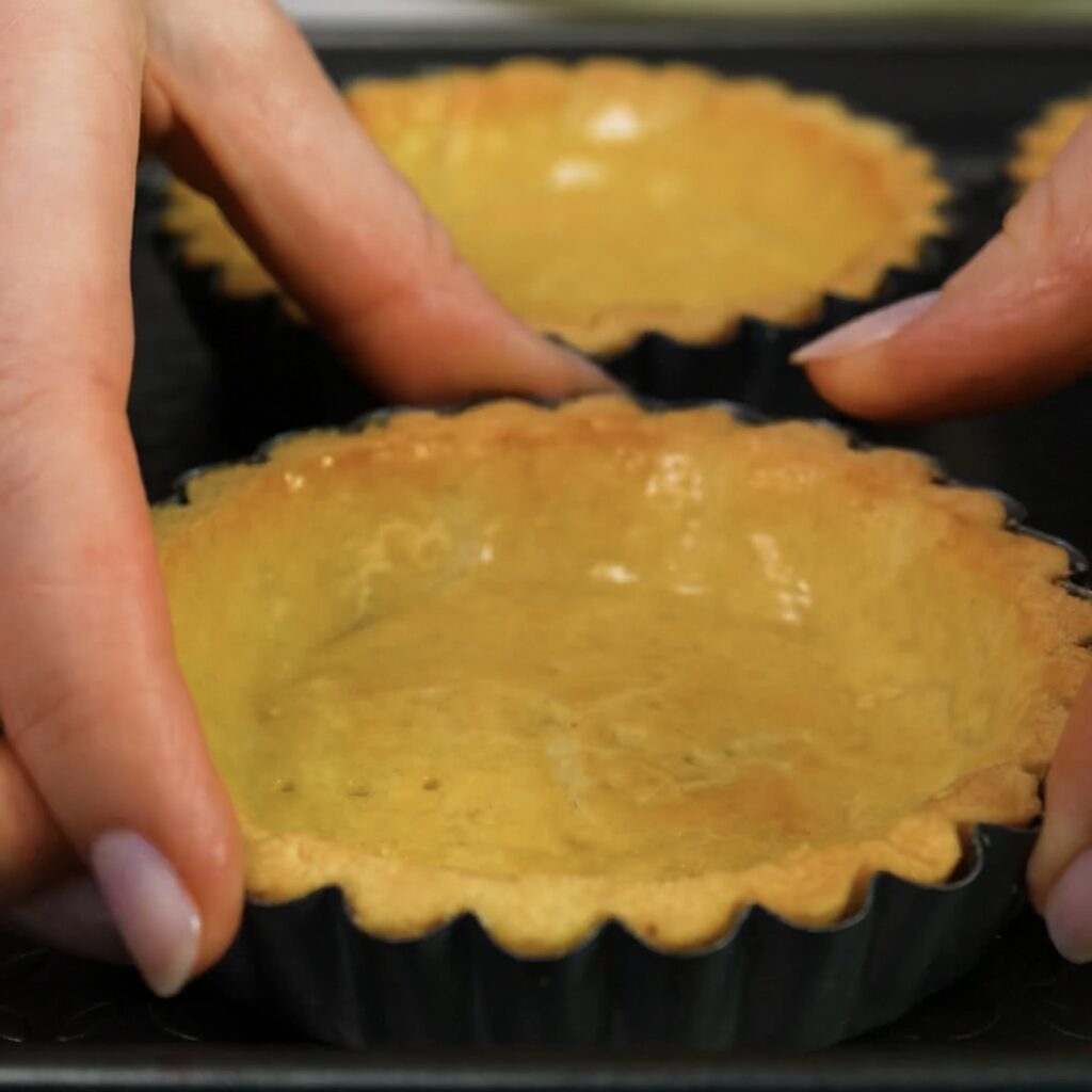 Golden pre-baked tart shells in mini tart tins.
