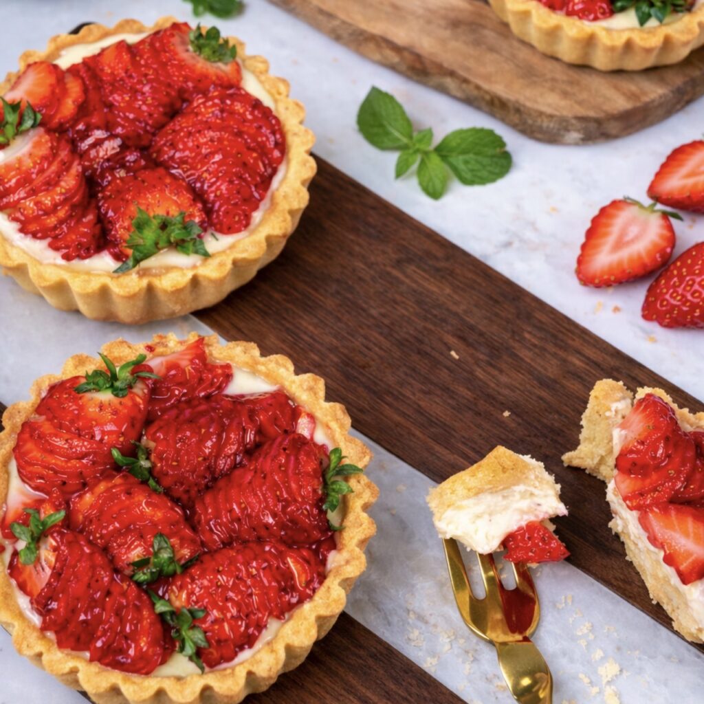 Strawberry ricotta tartlets served on a wooden board.