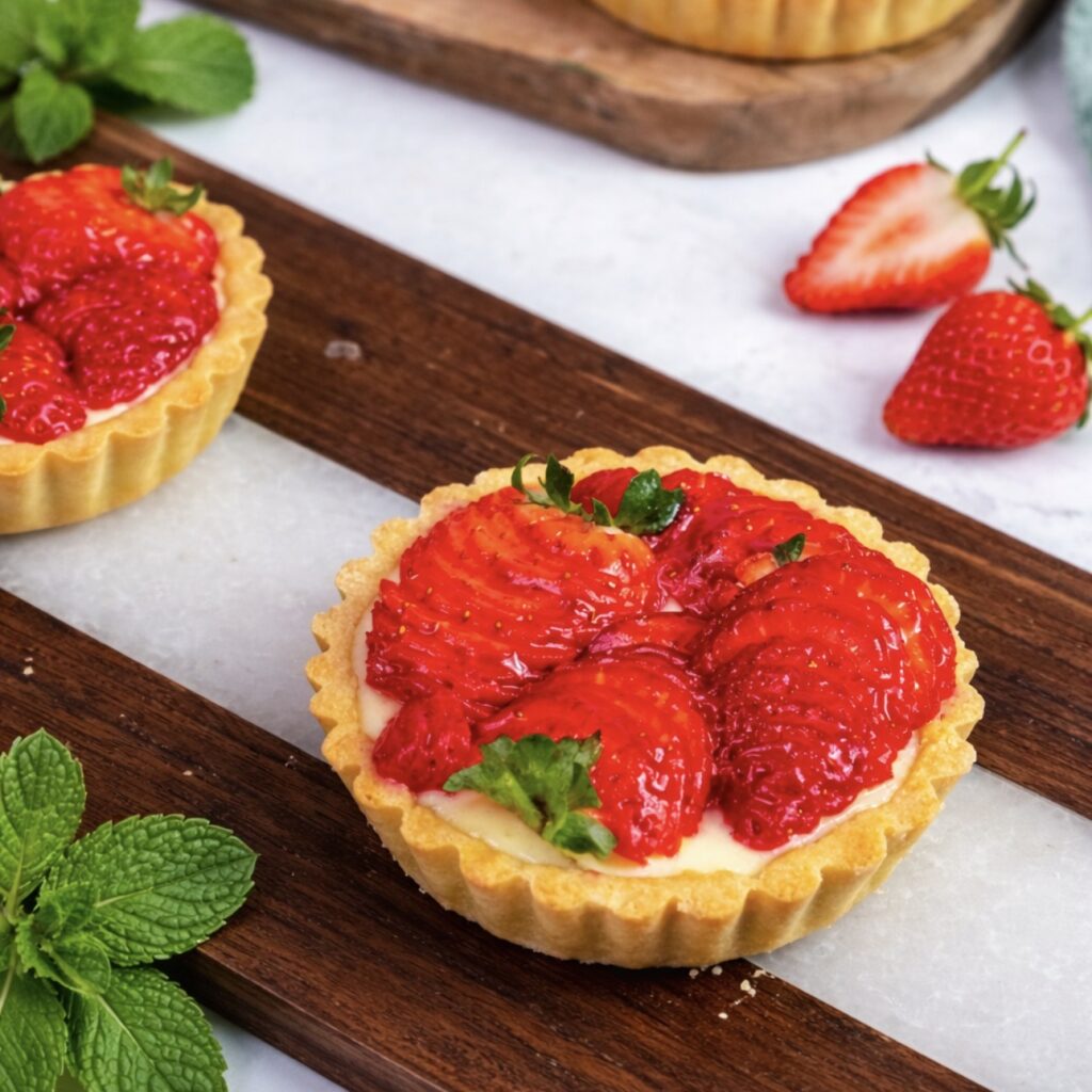 Strawberry ricotta tartlets served on a wooden board.