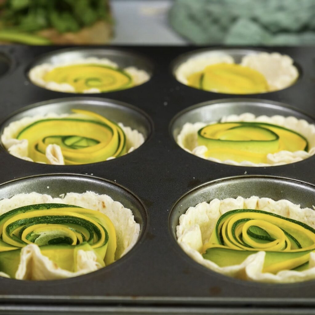 Courgette and squash spirals placed into tortilla cups in a muffin tin