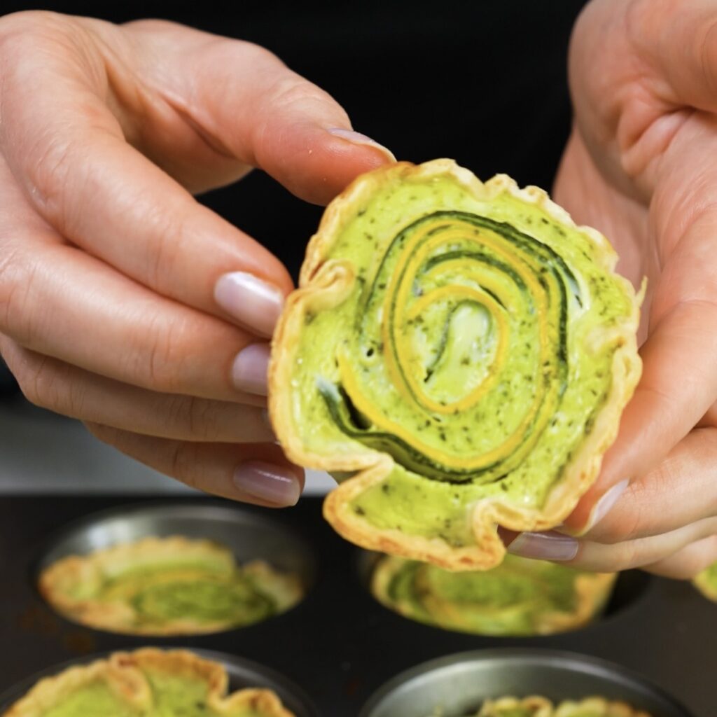 Hands holding a baked courgette tortilla quiche