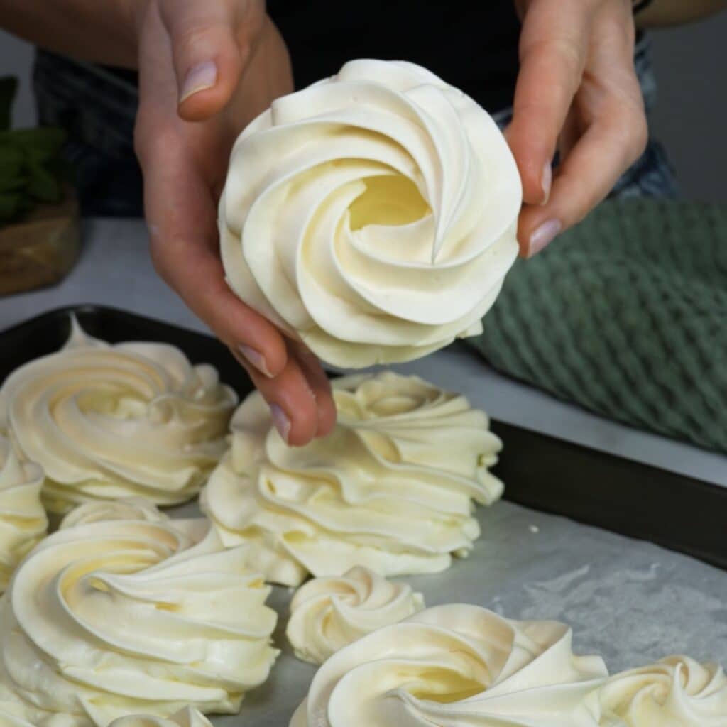 Hands holding a baked mini pavlova nest
