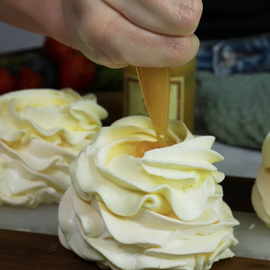 Adding peach curd on top of mini pavlova during assembly