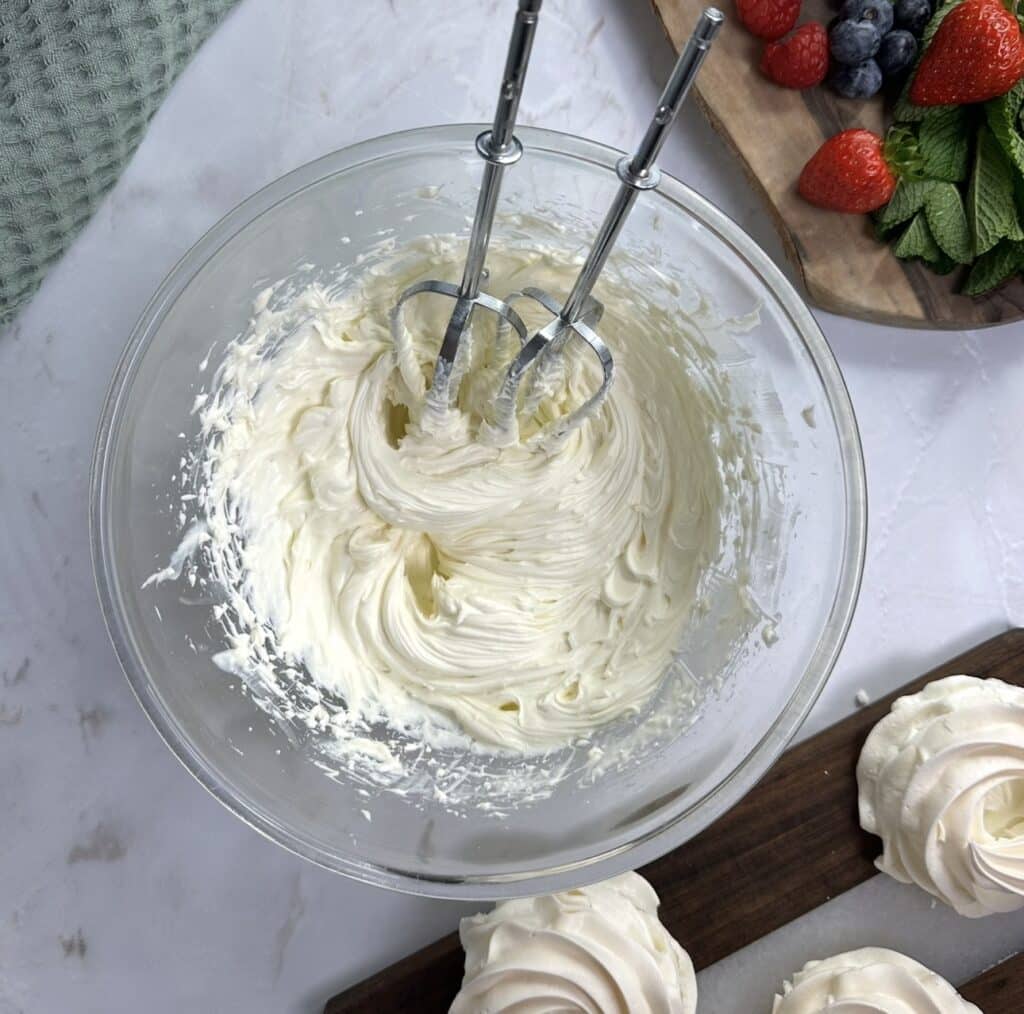 Cream cheese whipped cream filling for peach curd mini pavlovas in a mixing bowl