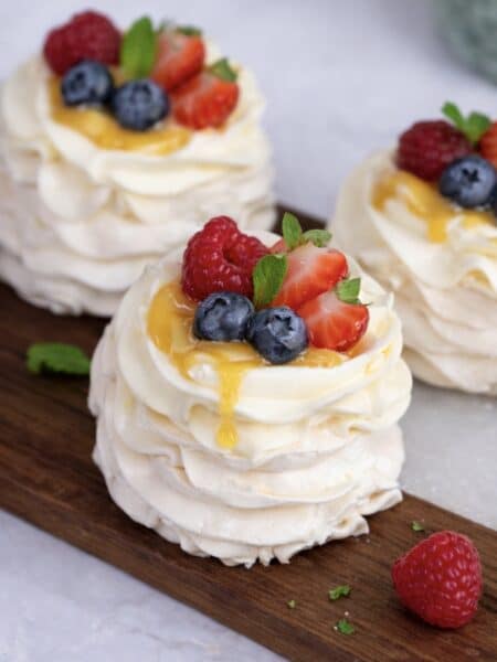 Peach curd mini pavlovas assembled and served on a wooden board