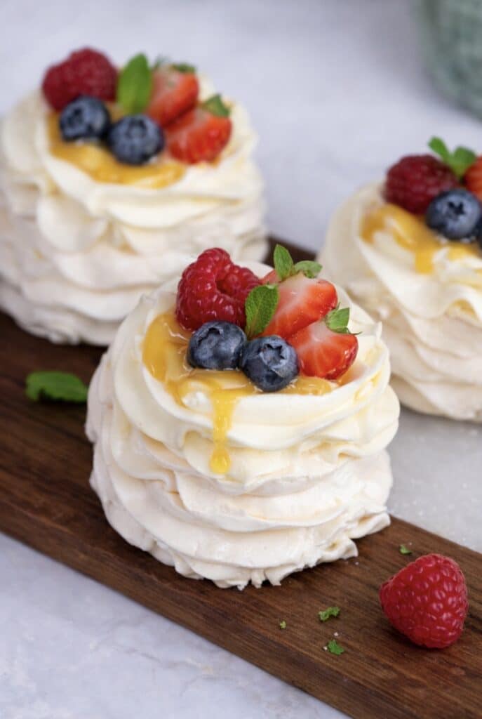Peach curd mini pavlovas assembled and served on a wooden board