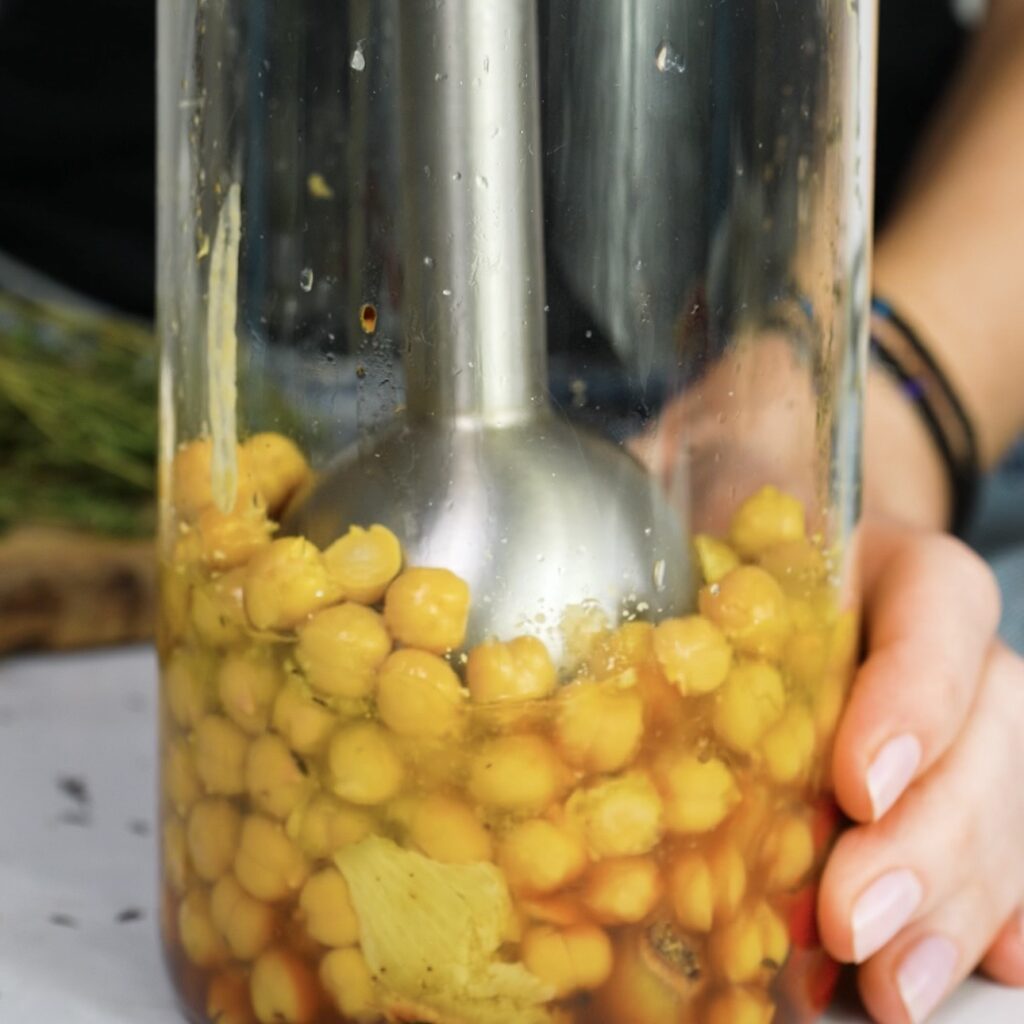 Blending roasted pepper hummus with an immersion blender until smooth