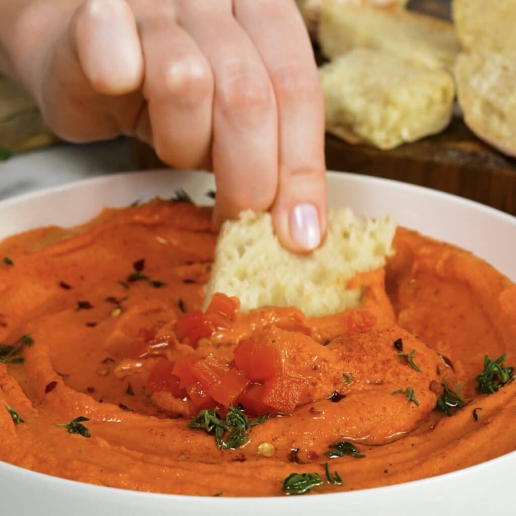 Dipping freshly baked ciabatta into roasted pepper hummus