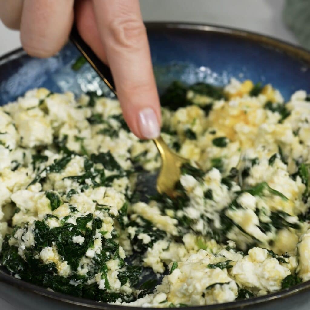 Mixing feta and spinach filling in a bowl for rice paper rolls