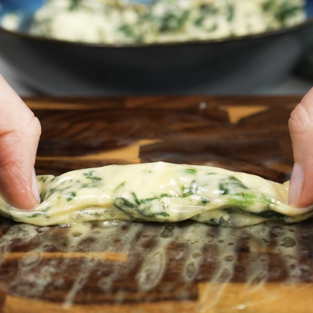 Rolling rice paper around feta and spinach filling into a tight roll