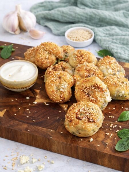 Feta and spinach rice paper rolls served on a wooden board with garlic yoghurt