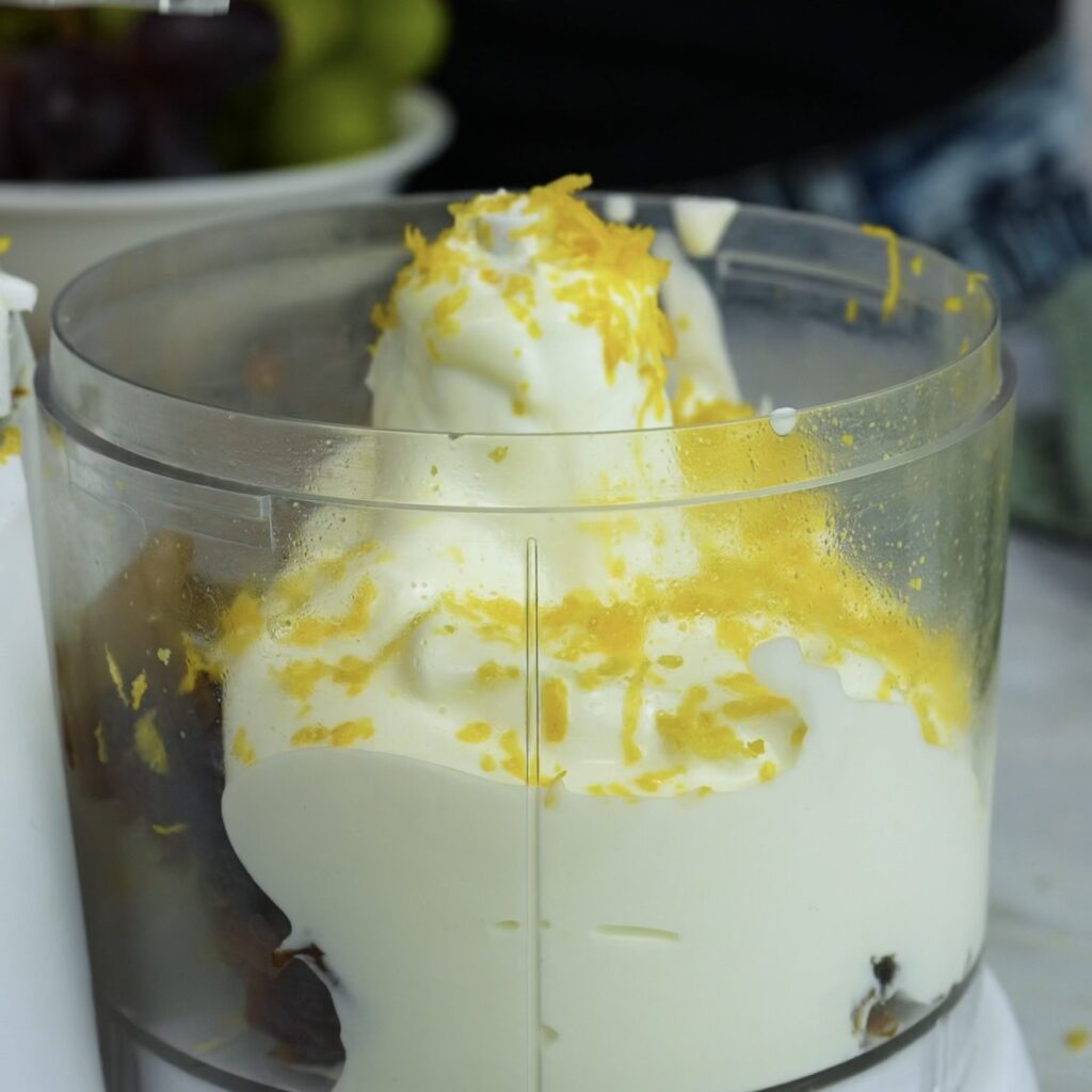 Dates, yogurt and lemon zest in a food processor ready to blend for frozen yogurt bars