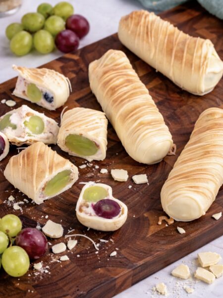 Whole and sliced grape yogurt bars on a wooden board
