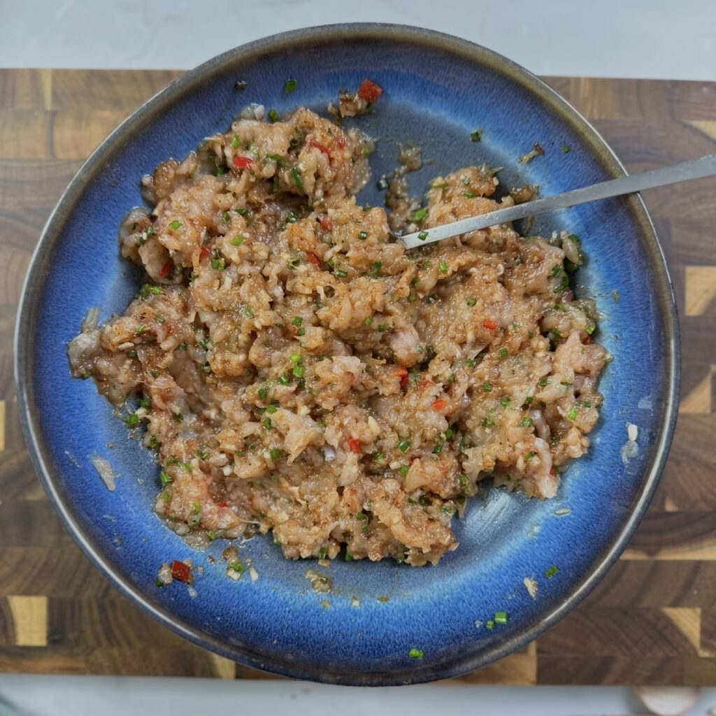 Minced chicken filling mixed with garlic, ginger, chilli and herbs in a bowl