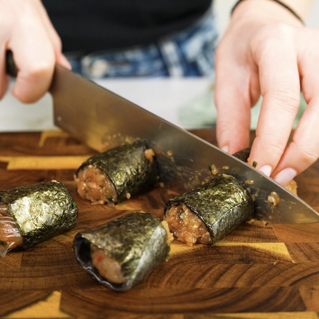 Slicing rice paper roll into six equal pieces on a cutting board