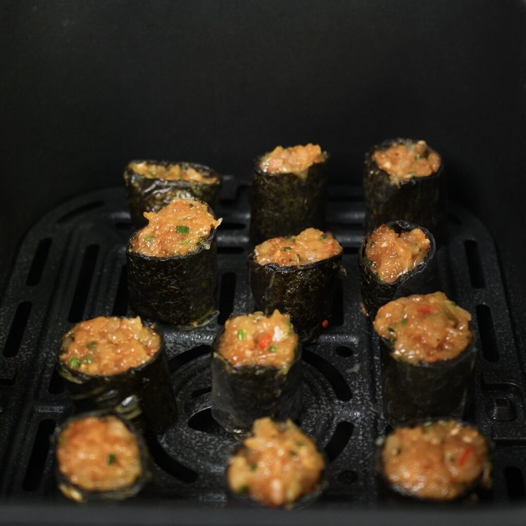 Mini rice paper rolls arranged in a single layer in an air fryer basket
