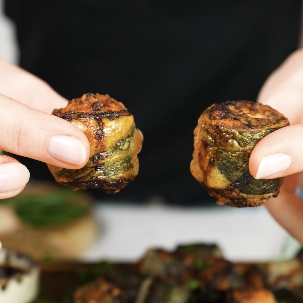 Hands holding two crispy rice paper rolls