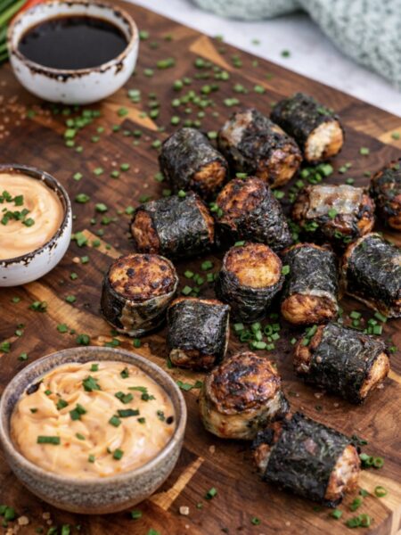 Crispy chicken rice paper rolls served on a wooden board with sriracha mayo and soy sauce