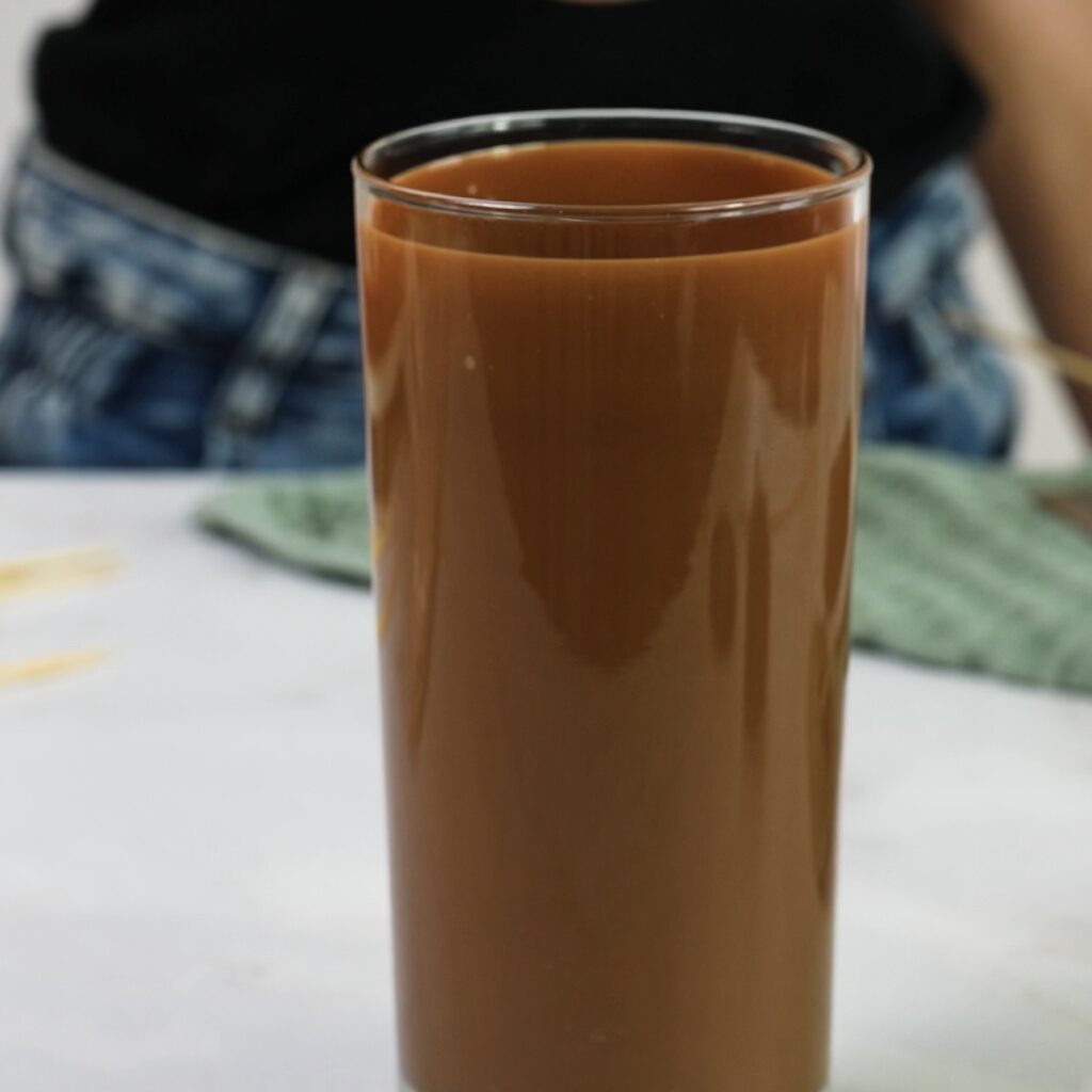 Smooth chocolate glaze in a tall glass ready for dipping bars