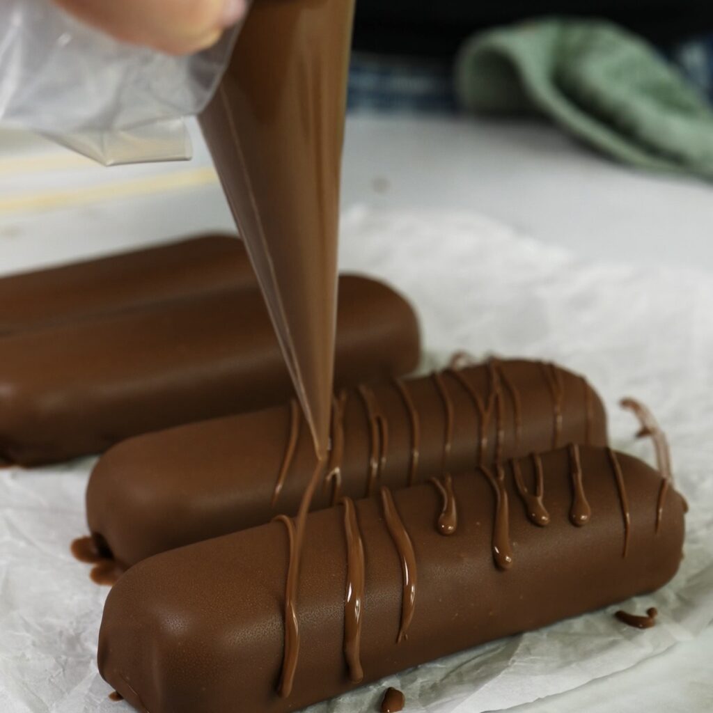 Drizzling melted chocolate over coated protein bars
