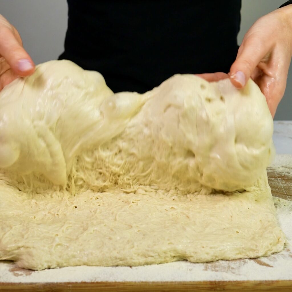 Folding ciabatta dough during shaping on floured surface