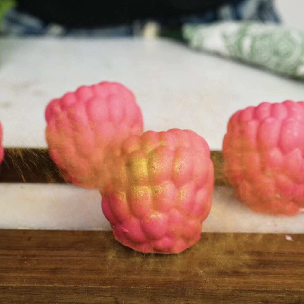 Dusting chocolate raspberry yogurt gems with edible gold dust