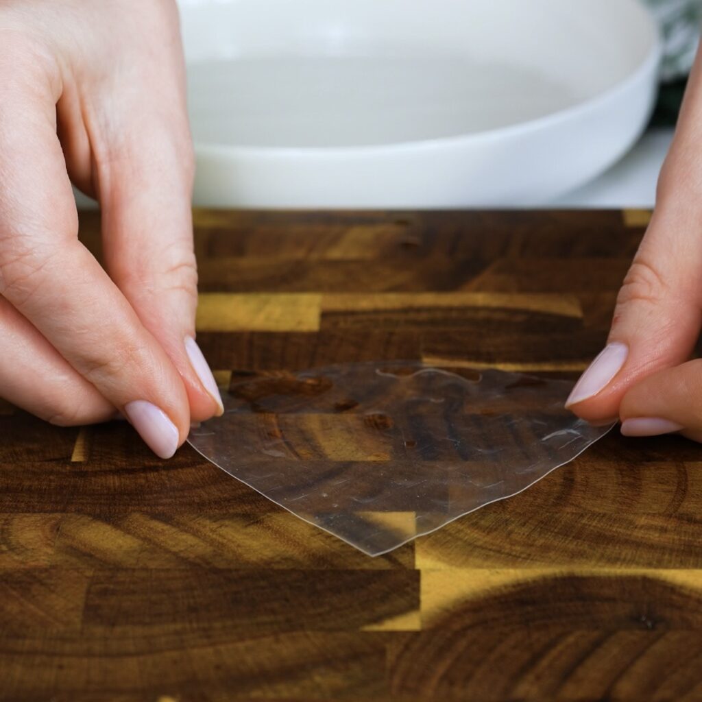 Quarter of rice paper sheet placed on a flat surface, ready for filling