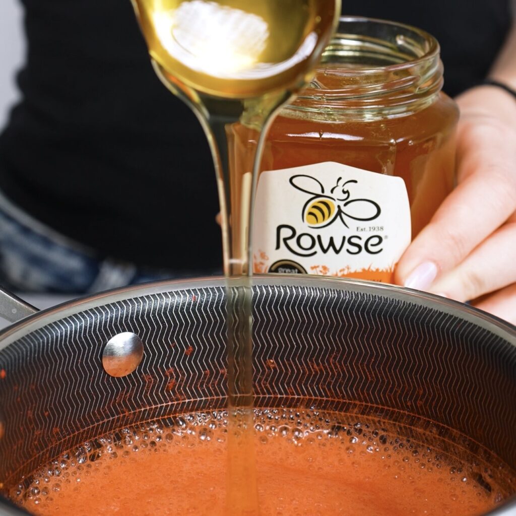 Adding honey to hot strawberry puree for strawberry fluff squares