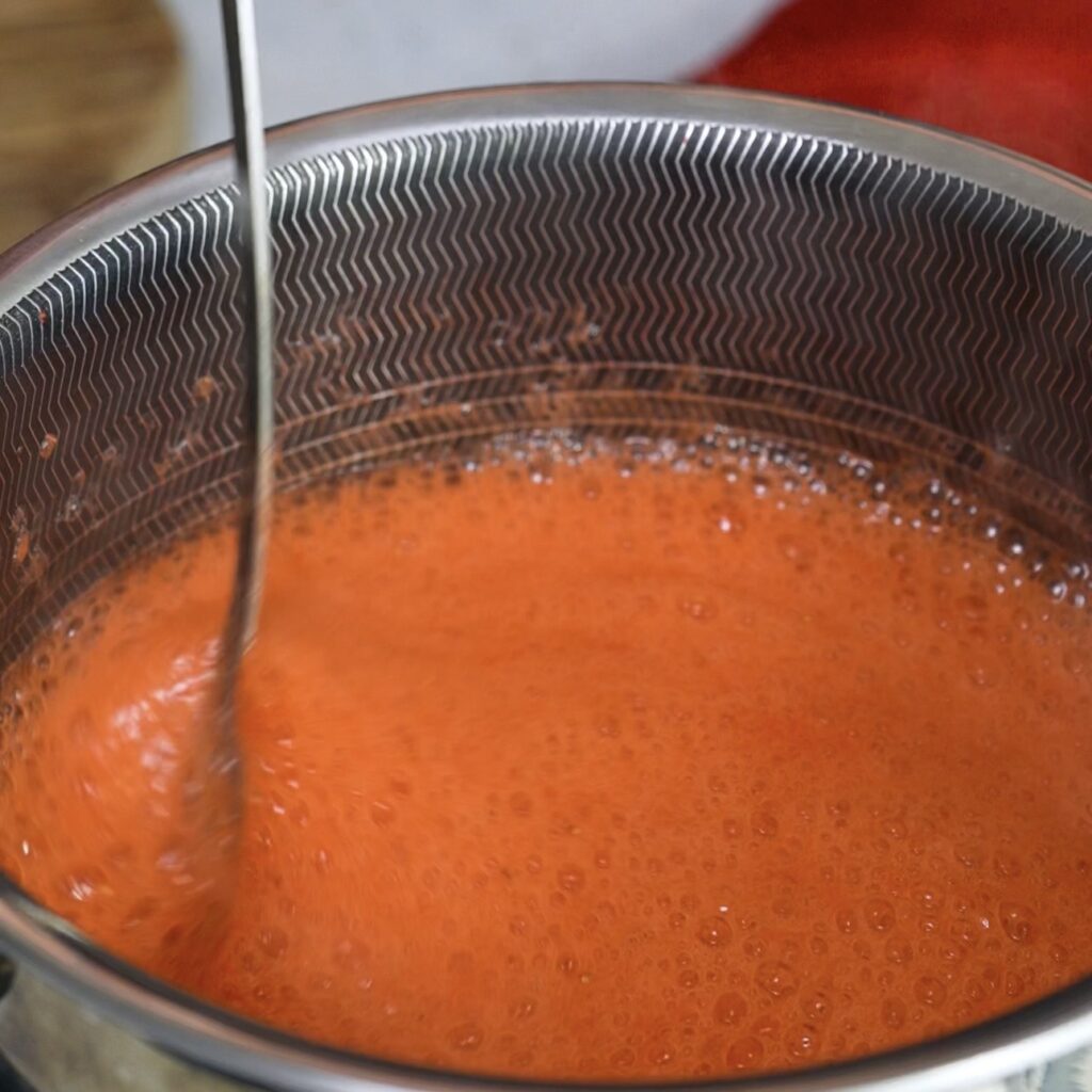 Cooking strawberry puree in a saucepan until smooth and heated