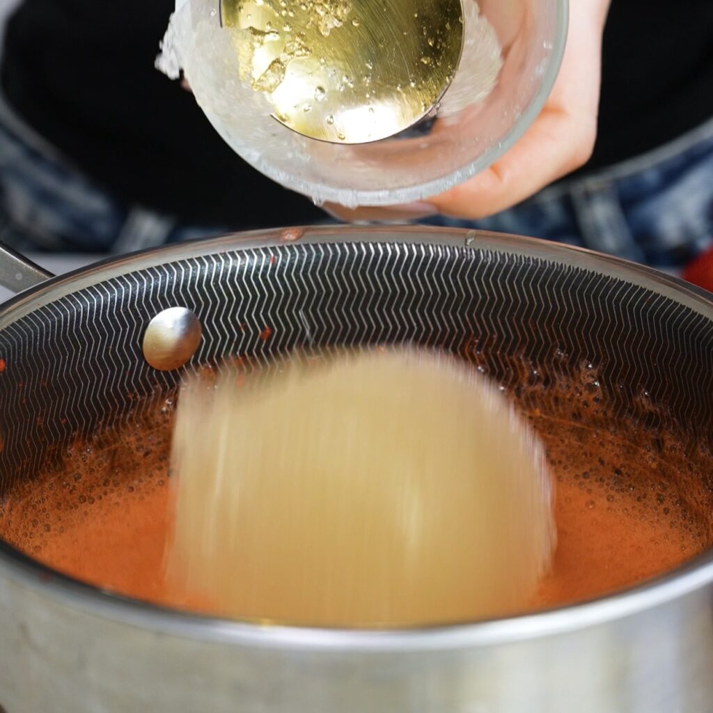Adding bloomed gelatine to warm strawberry puree