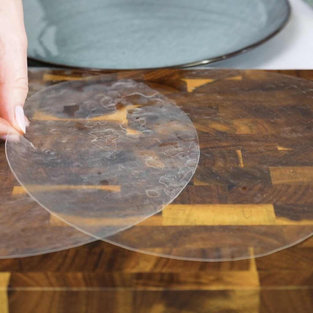 Two rice paper sheets overlapping on a flat surface to create a wider base for rolling
